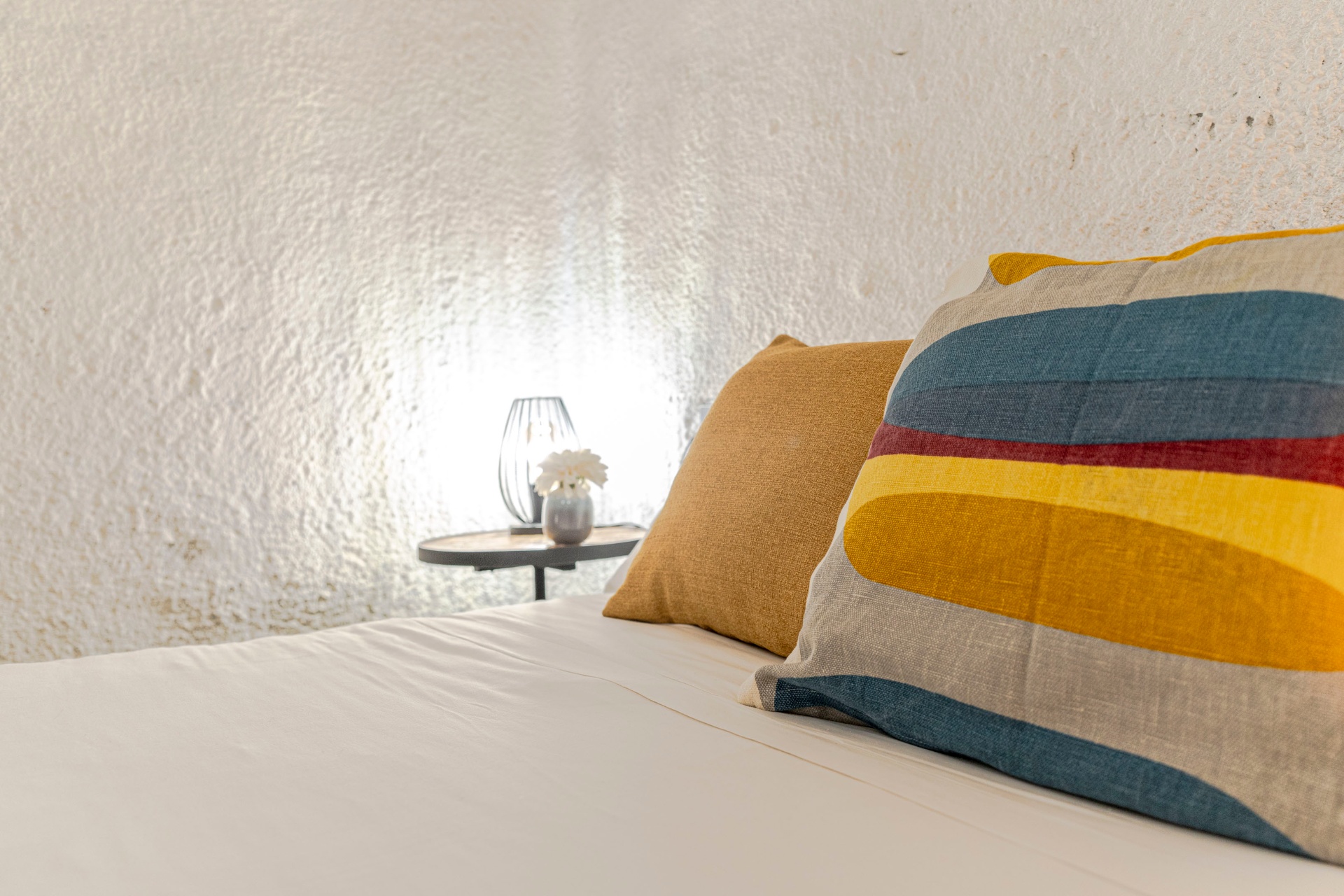 Detalle: cojines de acento y mesita de noche junto a la pared de cueva